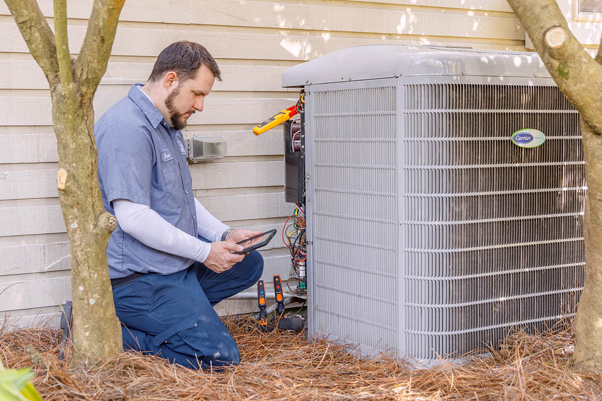 Carolina Air tech checking system Carolina Air HVAC professional servicing a heat pump